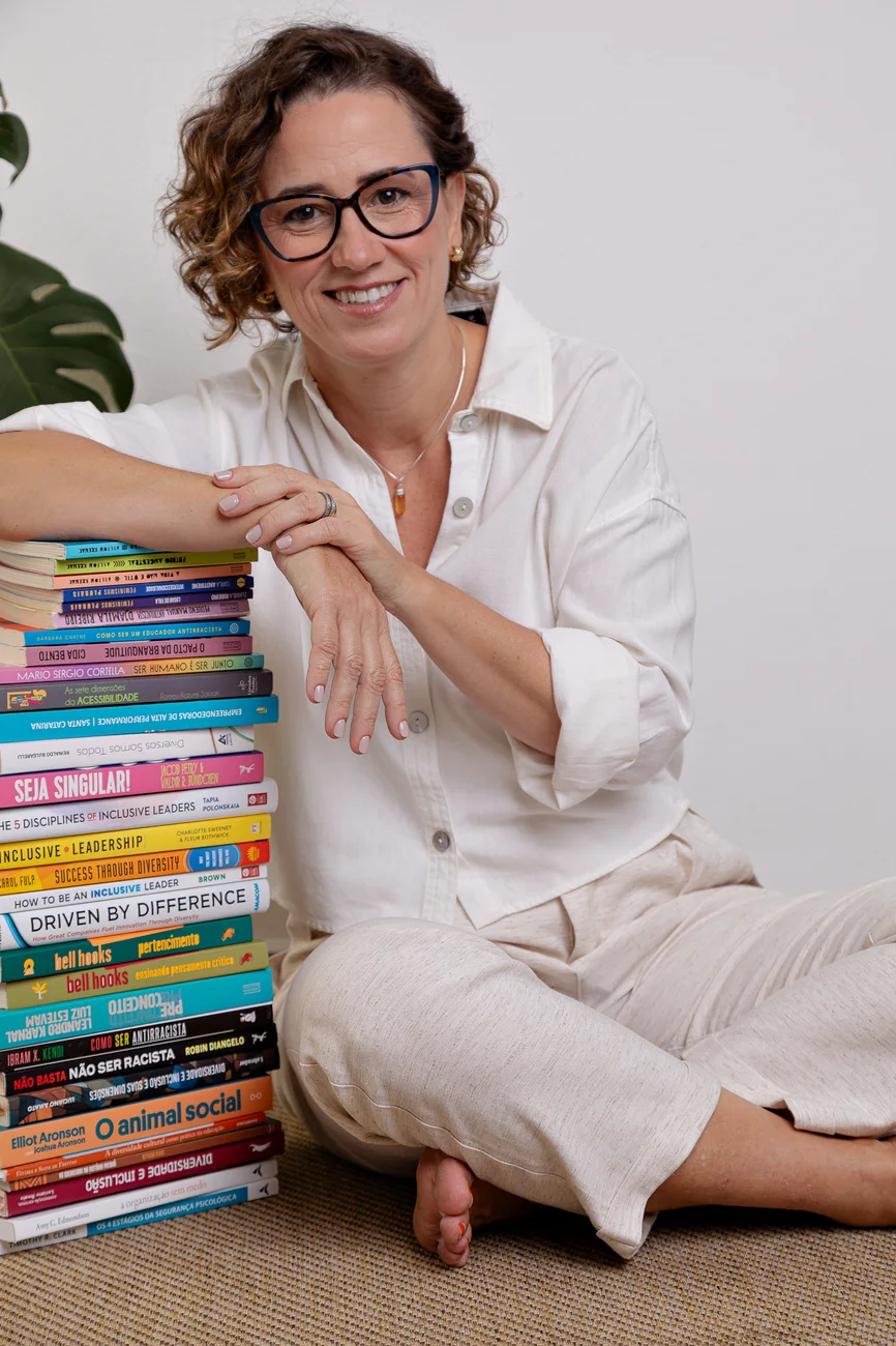 Viviane de Araújo sentada ao lado da pilha de seus livros publicados