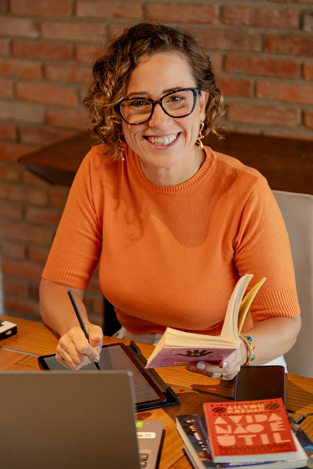 Viviane de Araújo escrevendo, ao lado de seus livros publicados